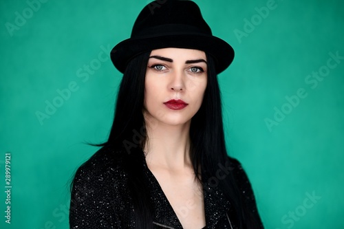 Concept close-up portrait of a pretty brunette girl in a hat on a colorful background in the studio.