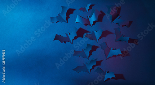 Halloween image of blue paper bats flying up on dark blue background. photo