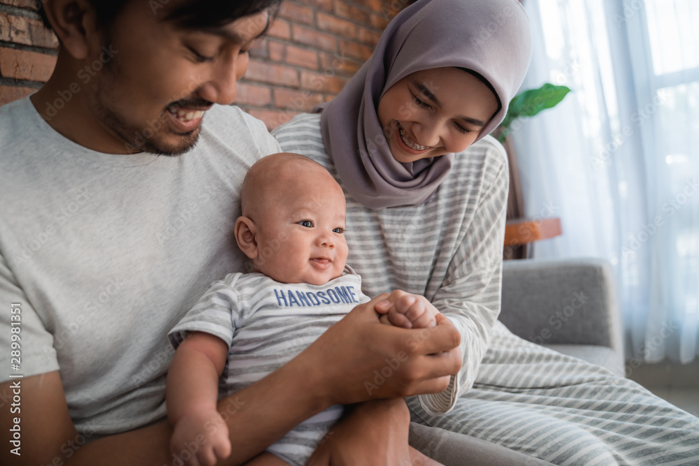 young asian family with infant son together smiling. muslim parenting young asian family with infant son together smiling. muslim parenting