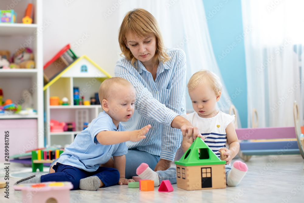 Nursery babies and kindergarten teacher playing with educational toys