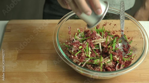 Process of making kimchi. A man pouring fish sauce into kimchi paste mix and stir with a spoon.