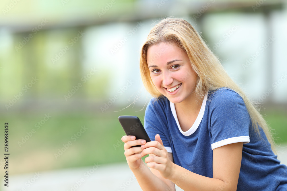 Teenage girl looking at camera holding smart phone Teenage girl looking at camera holding smart phone