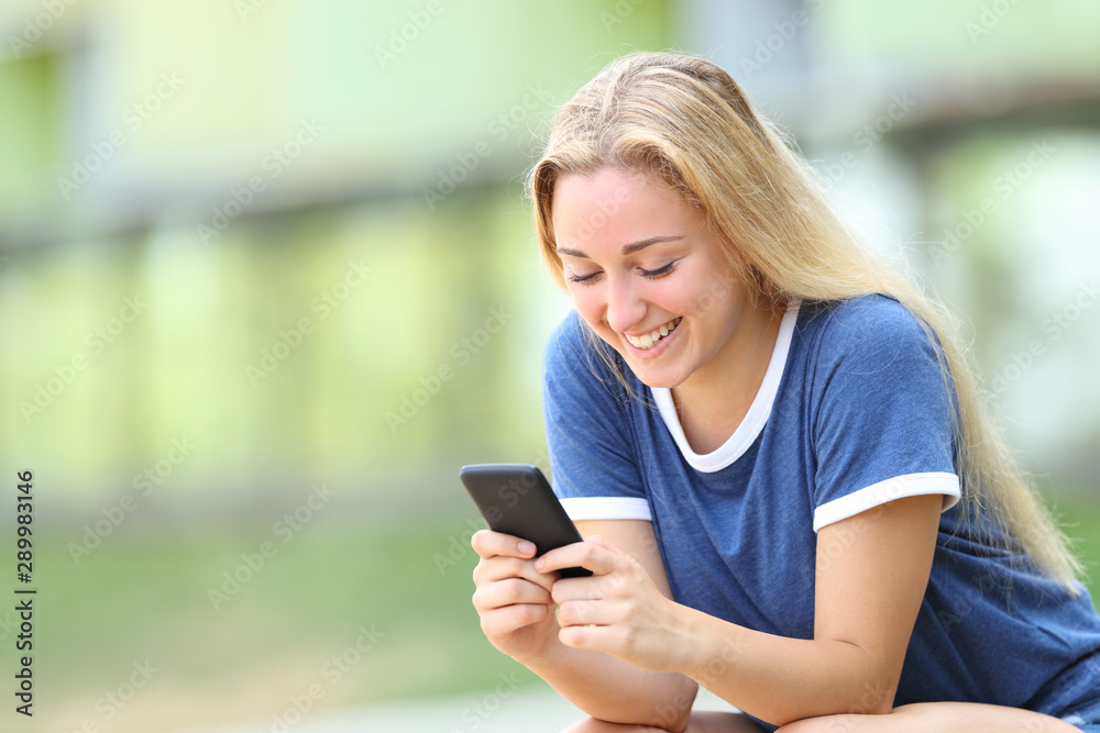 Happy teenage girl texing message on smart phone
