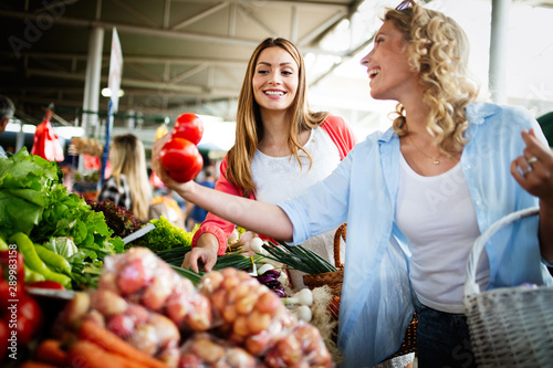 Young happy women shopping vegetables and fruits on the market photo