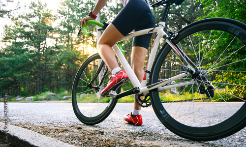 Young Woman Cyclist Riding Road Bicycle on the Free Road in the Forest at Hot Summer Day. Healthy Lifestyle Concept.