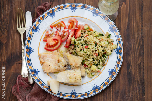 cod fish with quinoa and fresh salad on dish photo