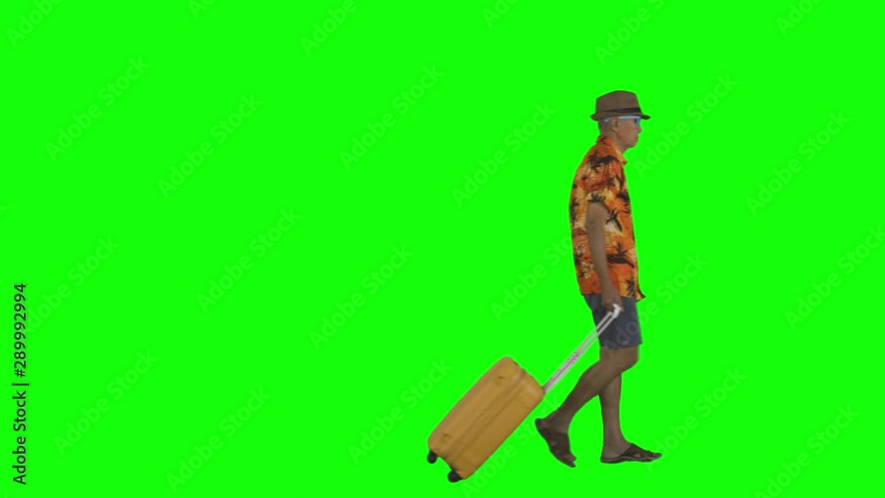 Funky elderly man walking in the studio while carrying suitcase for going vacation. Shot in 4k resolution with green screen background