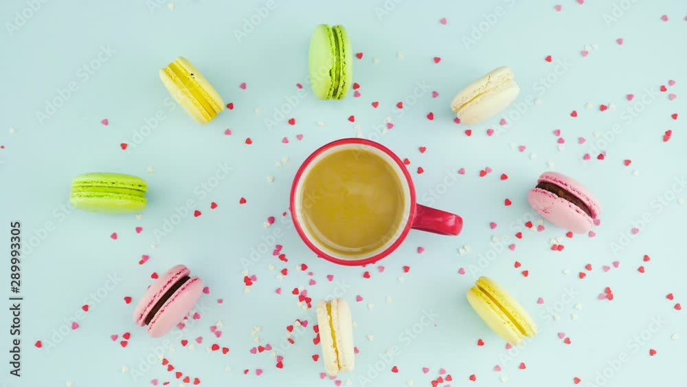 Macaroons or macaron on pastel blue surface with coffee in red cup. Macaroons or macaron on pastel blue surface with coffee in red cup.