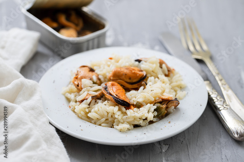 rice with mussels on small white plate on ceramic background