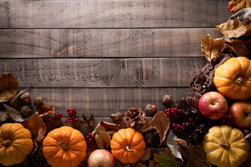 Top view of Autumn maple leaves with Pumpkin, apple, corn and red berries on old wooden background. Thanksgiving day concept.