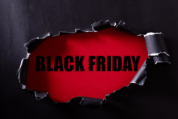 Top view of Black torn paper and the text black friday on a red background. Black Friday composition.