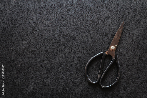 Black leather texture background with old vintage Scissors