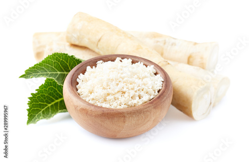 Fotografija Horseradish root and grated horseradish in wooden plate on white background