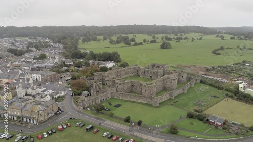 Beaumaris castle, Anglesey, Wales. Aerial view above coastal town fortification ruins tourist attraction. Ascending above town streets & historic landmark. photo