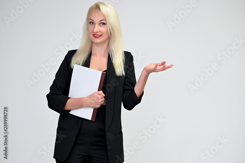 Concept portrait of a pretty young blonde woman with long beautiful hair in a black business suit with a folder in her hands on a white background in studio. Standing in different poses with a smile.