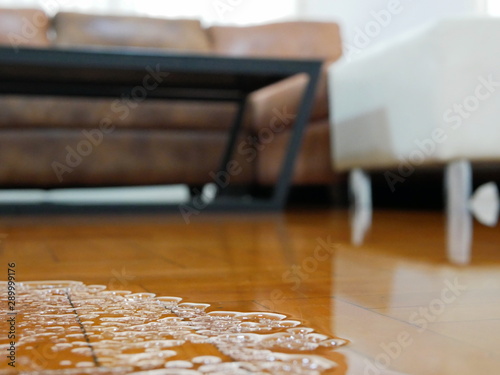 Close up of water flooding on living room parquet floor in a house - damage caused by water leakage