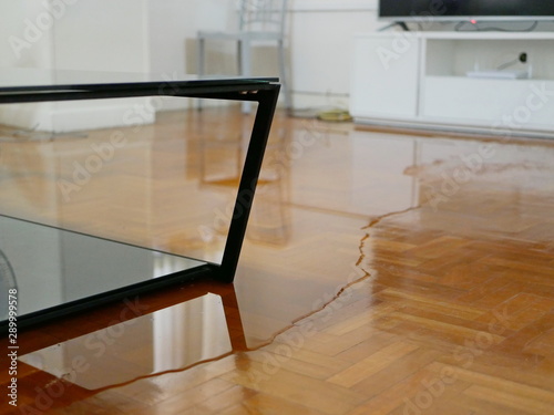 Close up of water flooding on living room parquet floor in a house - damage caused by water leakage
