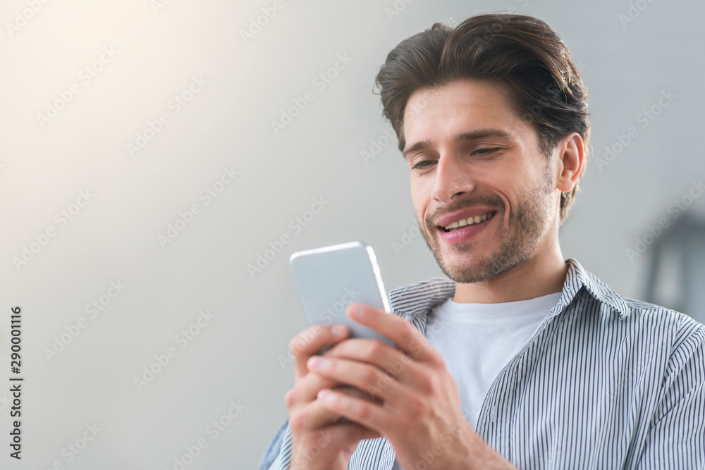 Cheerful millennial man texting with friend on cellphone Cheerful millennial man texting with friend on cellphone