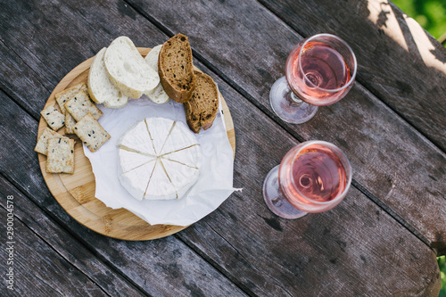 Camembert cheese, bread and crackers and two glasses of wine