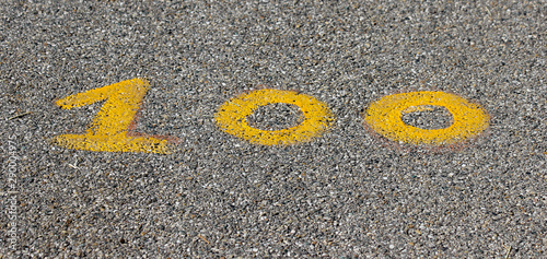 Arabic figure 100 (hundred) painted with yellow on an asphalt road