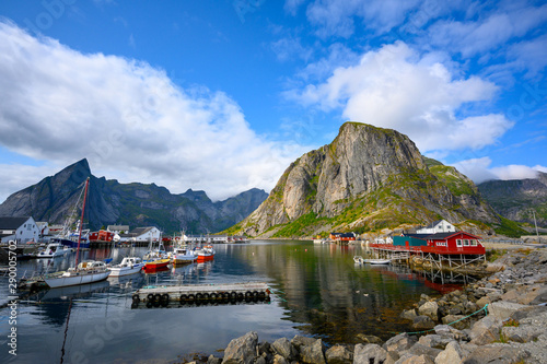 A fishing village at Hamnoy Reine, Norway during the daytime. The blue skies and mountains reflect the water.