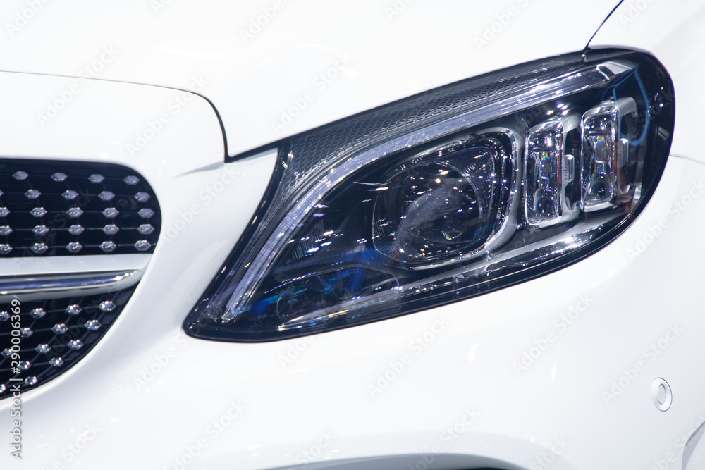 close up head lights , white color car front side view .