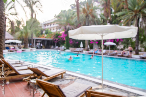 Summer vacation by the pool on comfortable wooden sun loungers among palm trees