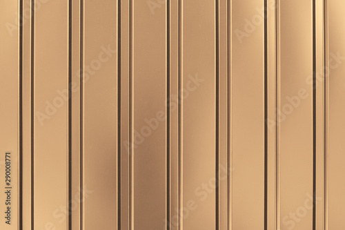 Gold background of metal wall siding, cladding. Fence with shiny, glitter. Reflecting metal convex texture. Light brown metallic striped surface. Abstract ribbed backgrounds.