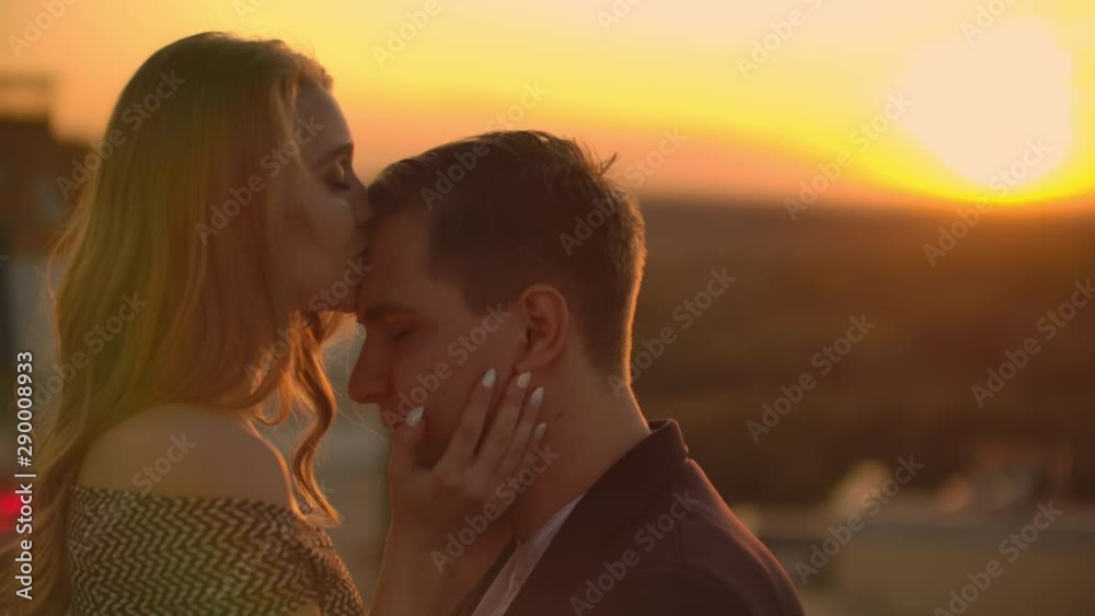 Lovely sweet happines couple sit on the roof top with amazing sunset view on the urban city town. They love each other hugs very tenderness sun goes between hair. Lovely sweet happines couple sit on the roof top with amazing sunset view on the urban city town. They love each other hugs very tenderness sun goes between hair.