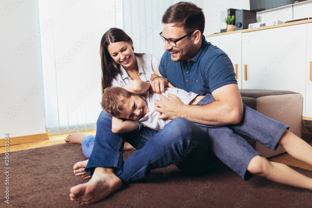 Smiling young parents and their child are very happy, they are at home, selective focus Smiling young parents and their child are very happy, they are at home, selective focus