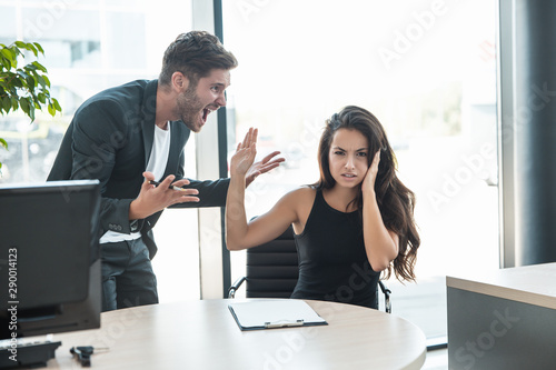 Foto strict boss man swearing at upset tired employee woman for bad work at the workp