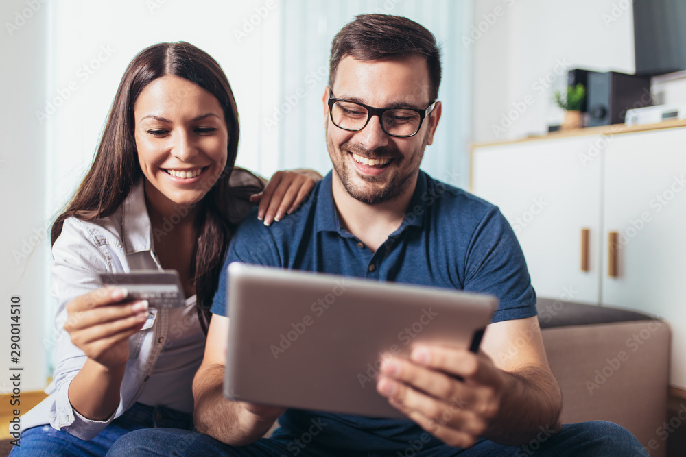 Smiling happy couple with tablet pc computer and credit or bank card shopping online at home Smiling happy couple with tablet pc computer and credit or bank card shopping online at home