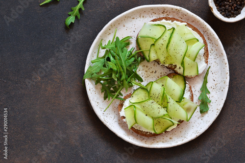 Lunch time. Bread toast with cheese, chopstick and cucumber on a concrete background. View from above.