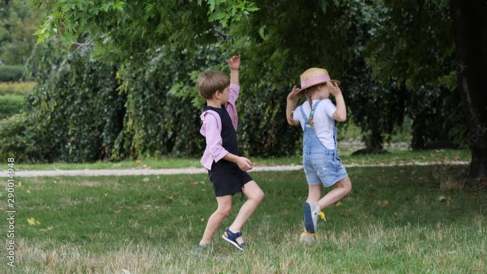 Funny children play together on park grass dancing jumping having fun Funny children play together on park grass dancing jumping having fun