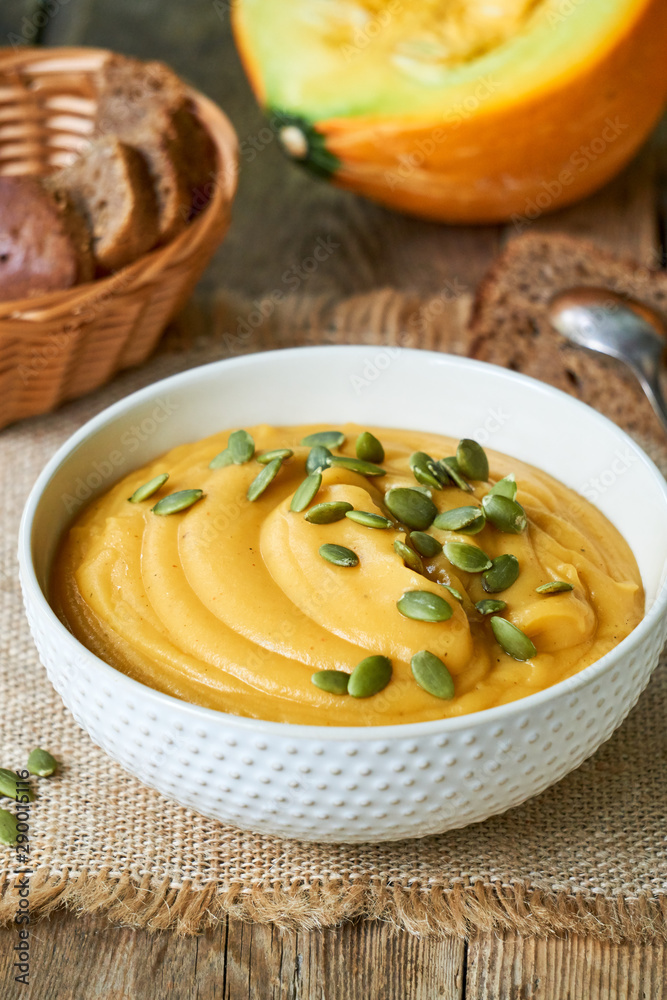 Thick pumpkin cream soup with seeds in a white bowl Thick pumpkin cream soup with seeds in a white bowl