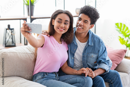 Young african couple taking selfie with smartphone at home