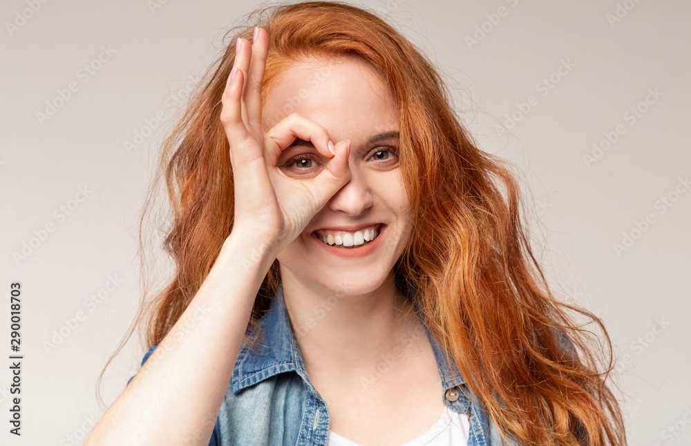 Playful redhead girl showing ok sign, gesturing with fingers Playful redhead girl showing ok sign, gesturing with fingers