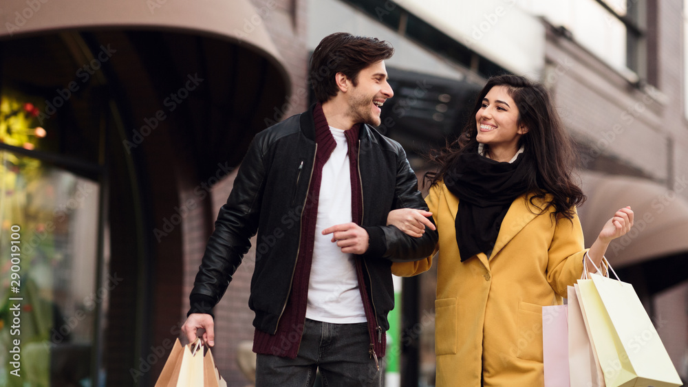 Shopping together. Young couple walking after shopping