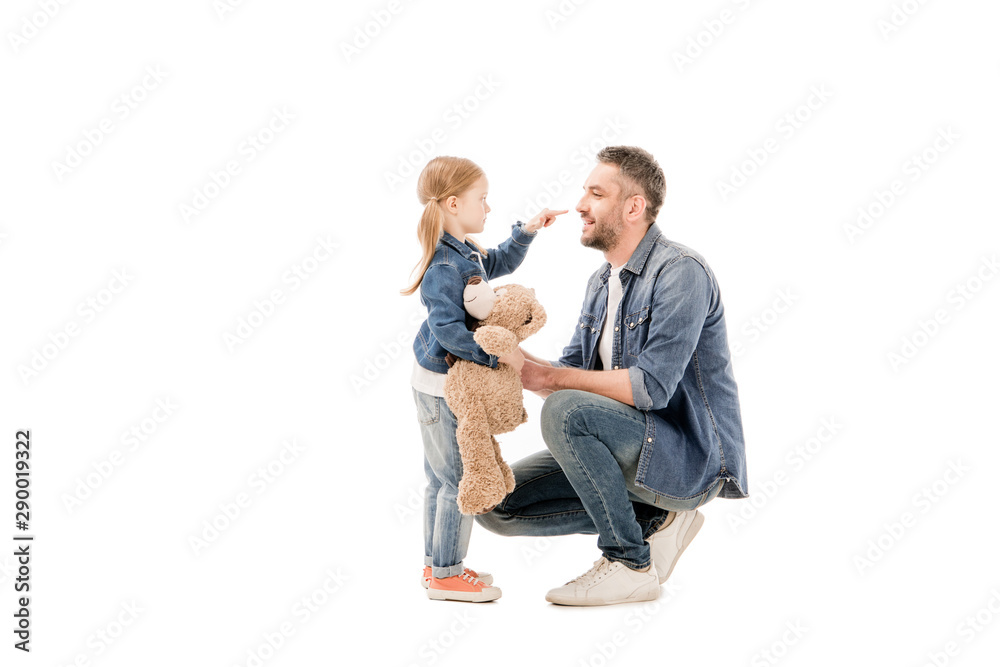 side view of daughter with teddy bear and bearded dad looking at each other isolated on white side view of daughter with teddy bear and bearded dad looking at each other isolated on white