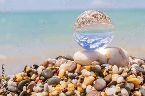 Glass round ball on the beach reflects the sea in summer