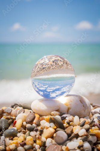 Glass round ball on the beach reflects the sea in summer