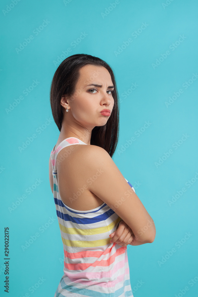 Brunette woman with long hair, dressed in colorful striped shirt, posing against blue studio background. Sincere emotions. Close-up. Brunette woman with long hair, dressed in colorful striped shirt, posing against blue studio background. Sincere emotions. Close-up.