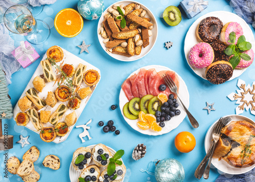 Overhead shoot of Chtistmas holiday food concept background with dinner party table over blue, top view, flat lay, bokeh