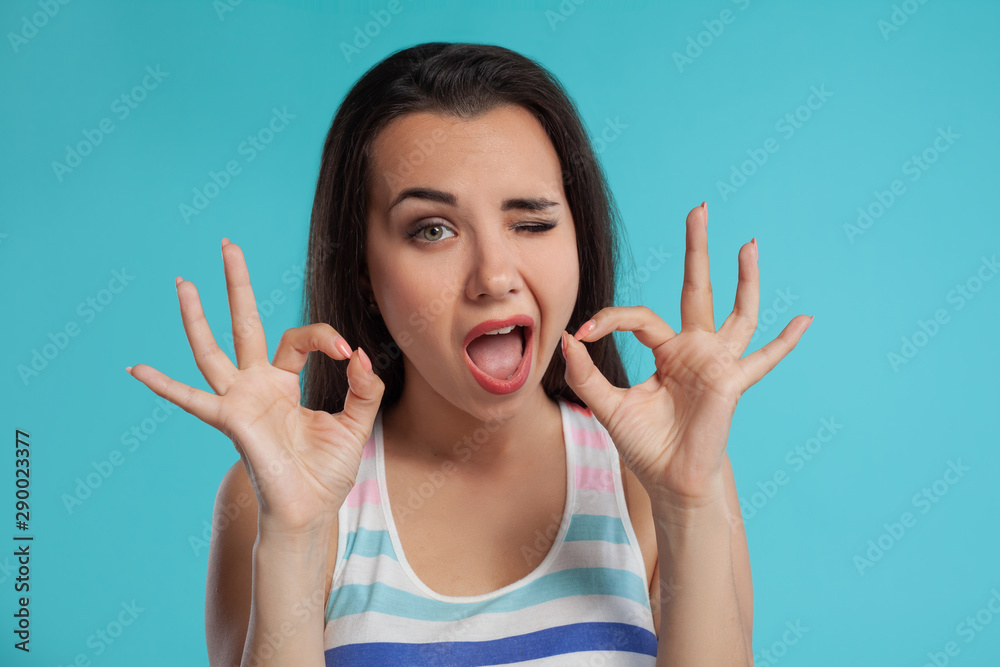 Brunette woman with long hair, dressed in colorful striped shirt, posing against blue studio background. Sincere emotions. Close-up. Brunette woman with long hair, dressed in colorful striped shirt, posing against blue studio background. Sincere emotions. Close-up.