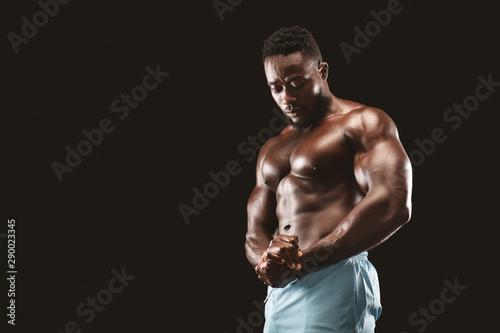 African bodybuilder showing muscular chest in black studio