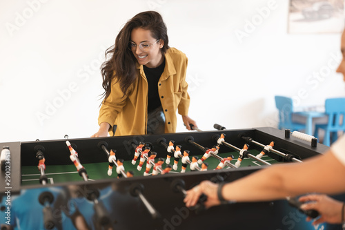 young happy brunette beautiful woman playing table football with her colleague during break at the office photo