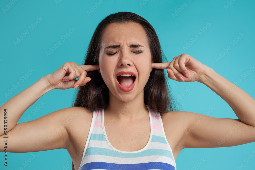 Brunette woman with long hair, dressed in colorful striped shirt, posing against blue studio background. Sincere emotions. Close-up. Brunette woman with long hair, dressed in colorful striped shirt, posing against blue studio background. Sincere emotions. Close-up.