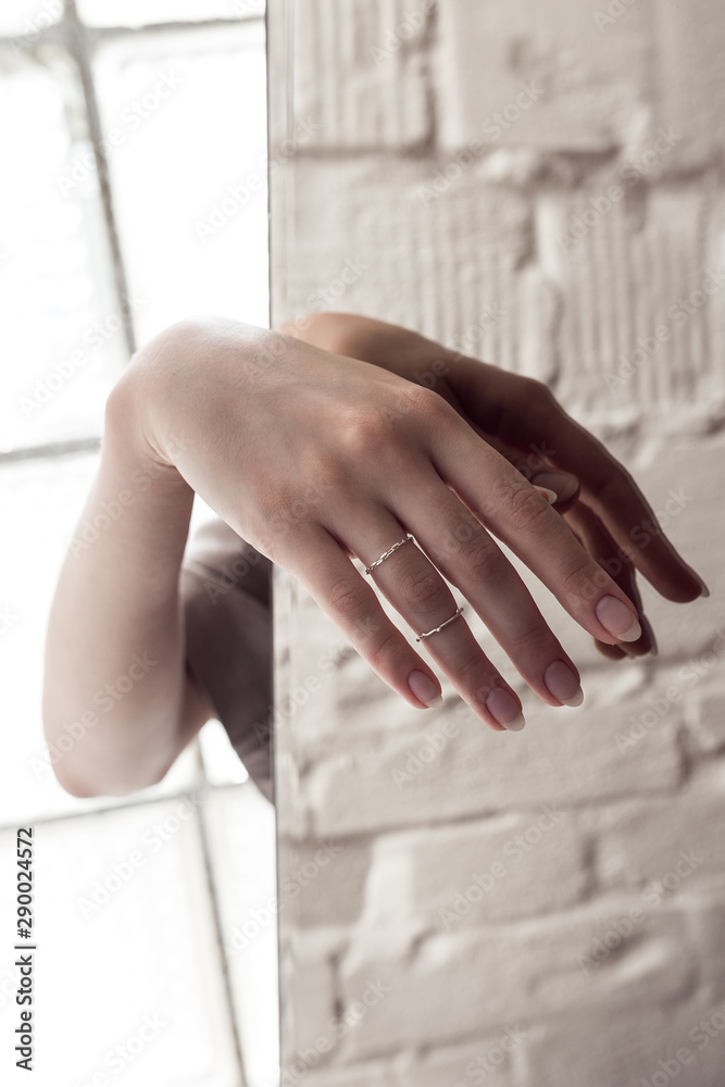 Beautiful womans' hand reflected in mirror, manicure and silver jewelry. 