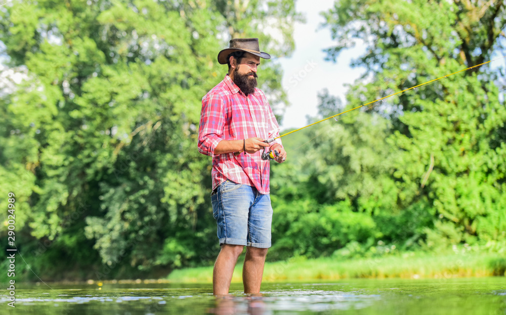 Some kind meditation. Fish normally caught in wild. Trout farm. Hobby sport activity. Calm and peaceful mood. Fisherman alone stand in river water. Man bearded fisherman. Fisherman fishing equipment