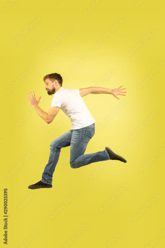 Full length portrait of happy jumping man isolated on yellow background. Caucasian male model in casual clothes. Freedom of choices, inspiration, human emotions concept. Run for sales, hurry up. Full length portrait of happy jumping man isolated on yellow background. Caucasian male model in casual clothes. Freedom of choices, inspiration, human emotions concept. Run for sales, hurry up.